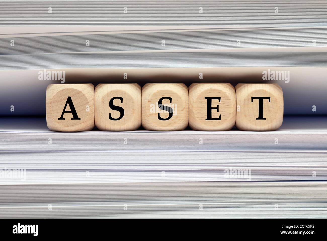La parola risorsa su cubi di legno contro pila di file e cartelle sfondo. Risorse aziendali, contabilità finanziaria o concetto di gestione patrimoniale. Foto Stock