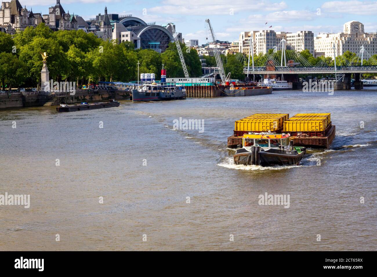 Rimorchiatore barca che tira il trasporto come contenitori in un grande separato Chiatta lungo il Tamigi a Londra Foto Stock