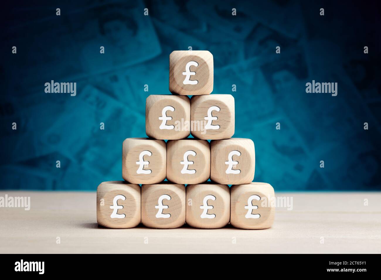 Sterlina inglese simbolo su cubi di legno contro sfondo di denaro. Riserve finanziarie, crescita, profitto, investimenti o risparmi nel concetto di business. Foto Stock