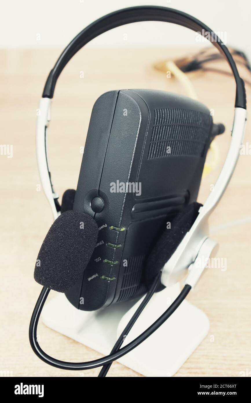 Modem ADSL con cuffie e microfono su tavolo di legno con messa a fuoco selettiva Foto Stock