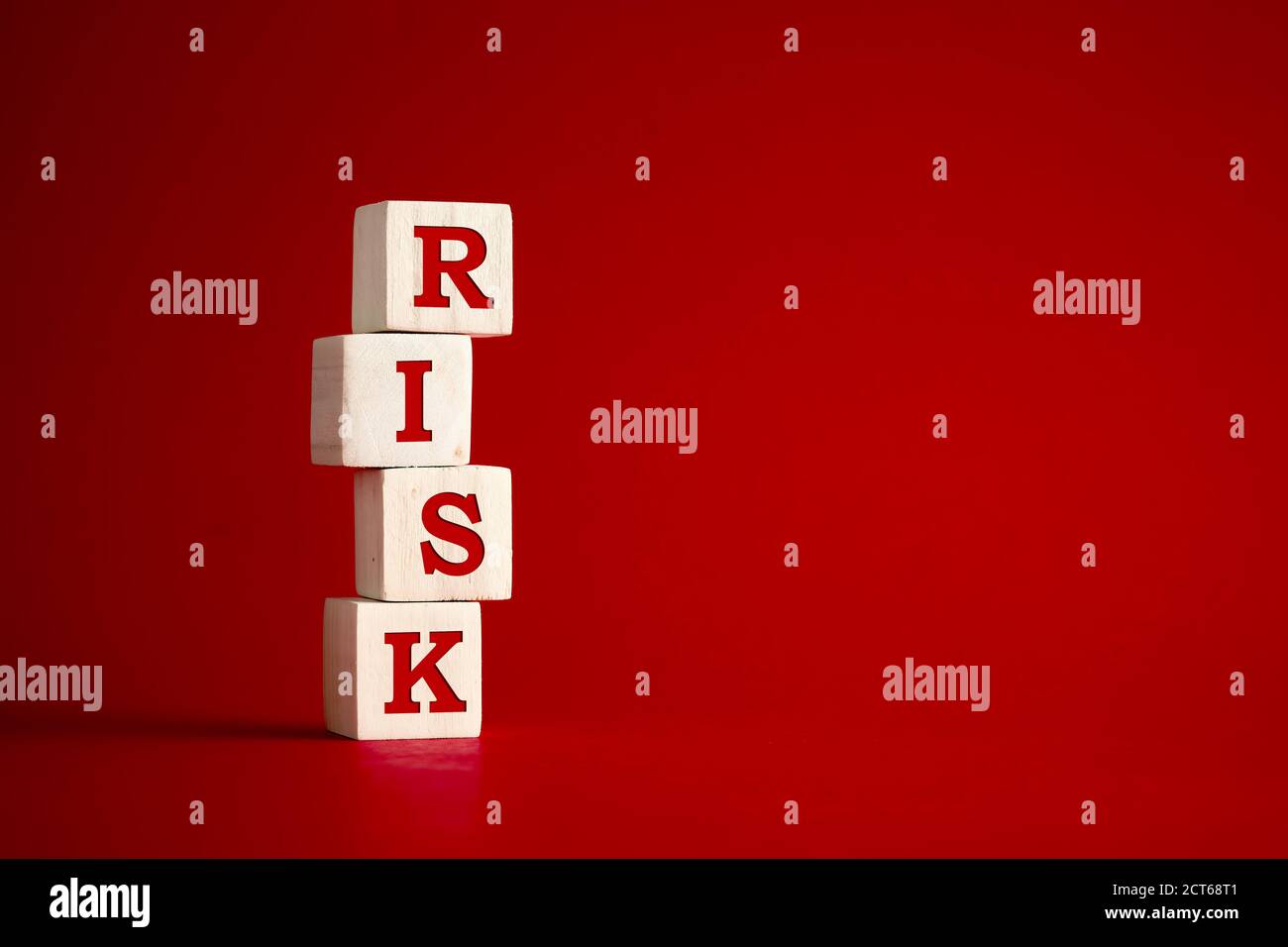 La parola rischio su cubi di legno su sfondo rosso. Rischio e incertezza nel concetto di strategia aziendale e decisionale. Foto Stock