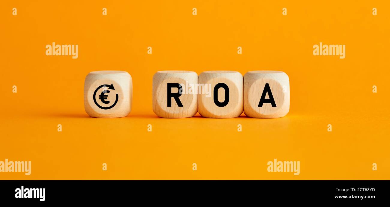 La parola ROA ritorno sui beni scritti su cubi di legno con su sfondo giallo. Analisi dei profitti o delle perdite nel concetto di business e finanza. Foto Stock