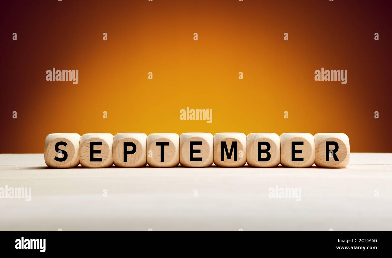 Il mese di settembre scritto su cubetti di legno con sfondo autunno con spazio di copia. Mese dell'anno. Foto Stock
