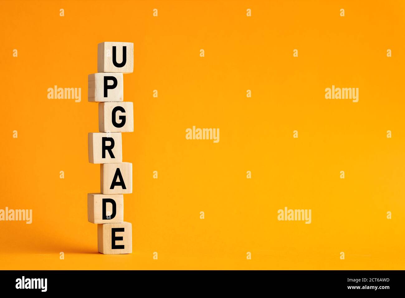 La parola upgrade su cubi di legno su sfondo giallo. Concetto di aggiornamento della tecnologia aziendale per computer, rete e Internet. Foto Stock