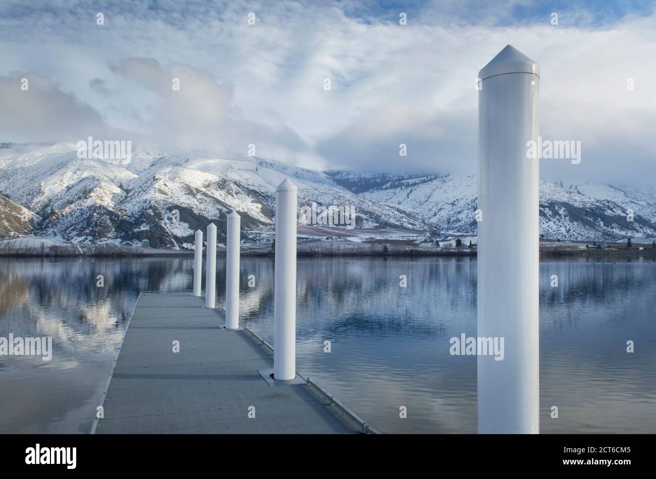 Pilastri sul dock a lago vicino coperta di neve la gamma della montagna Foto Stock