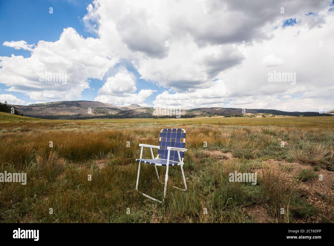 Sedia pieghevole singola su una pianura, montagne in lontananza. Foto Stock