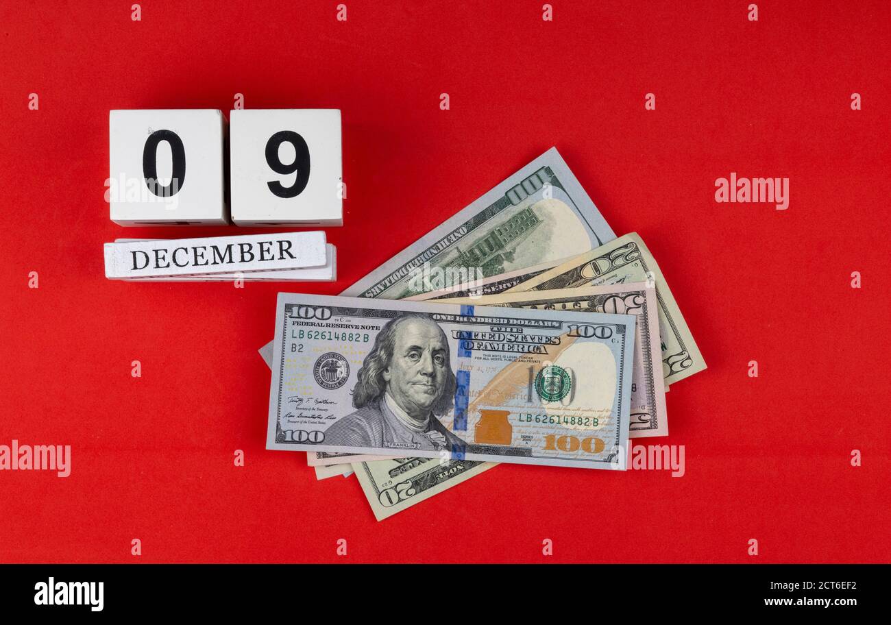 calendario e denaro su sfondo rosso. Cubo di legno fatto a mano con data mese e giorno. Giornata internazionale contro la corruzione Foto Stock