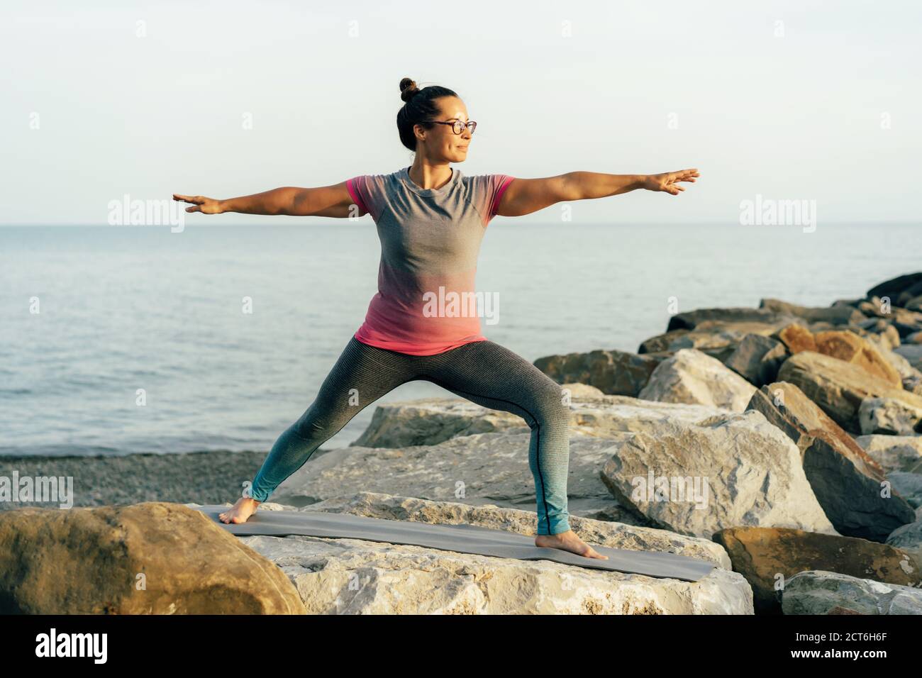 Giovane donna che pratica yoga in riva al mare Foto Stock