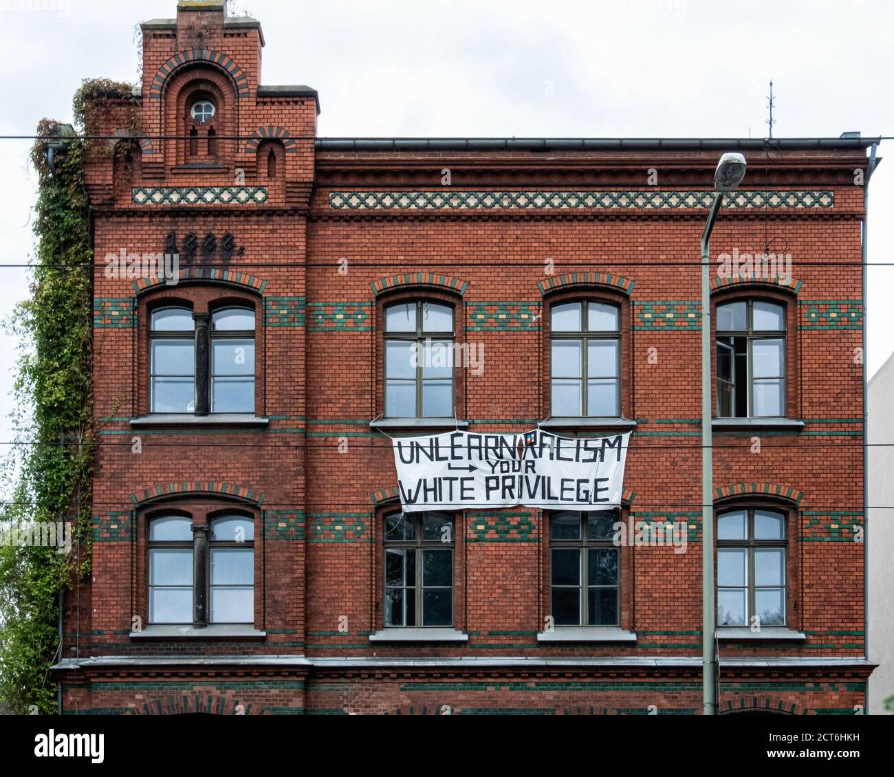 Poster sullo storico edificio in mattoni, Unlearn Your Racism and White Privilege, Eberswalder Strasse 10, Prenzlauer Berg, Berlino Foto Stock