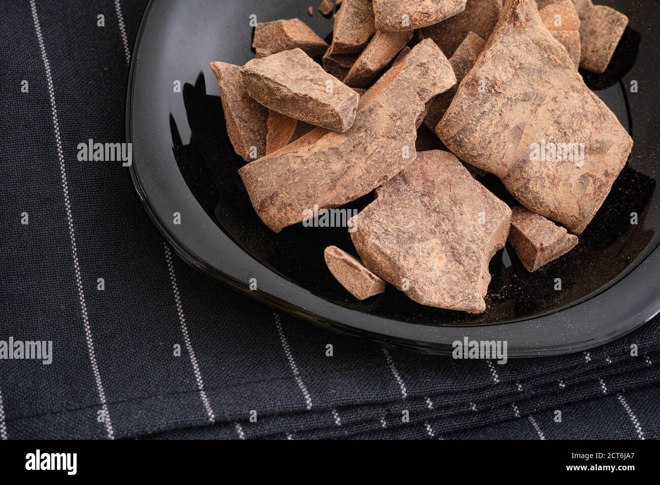 Pasta di cacao in una piastra nera. Theobroma cacao. Tasto basso. Foto Stock