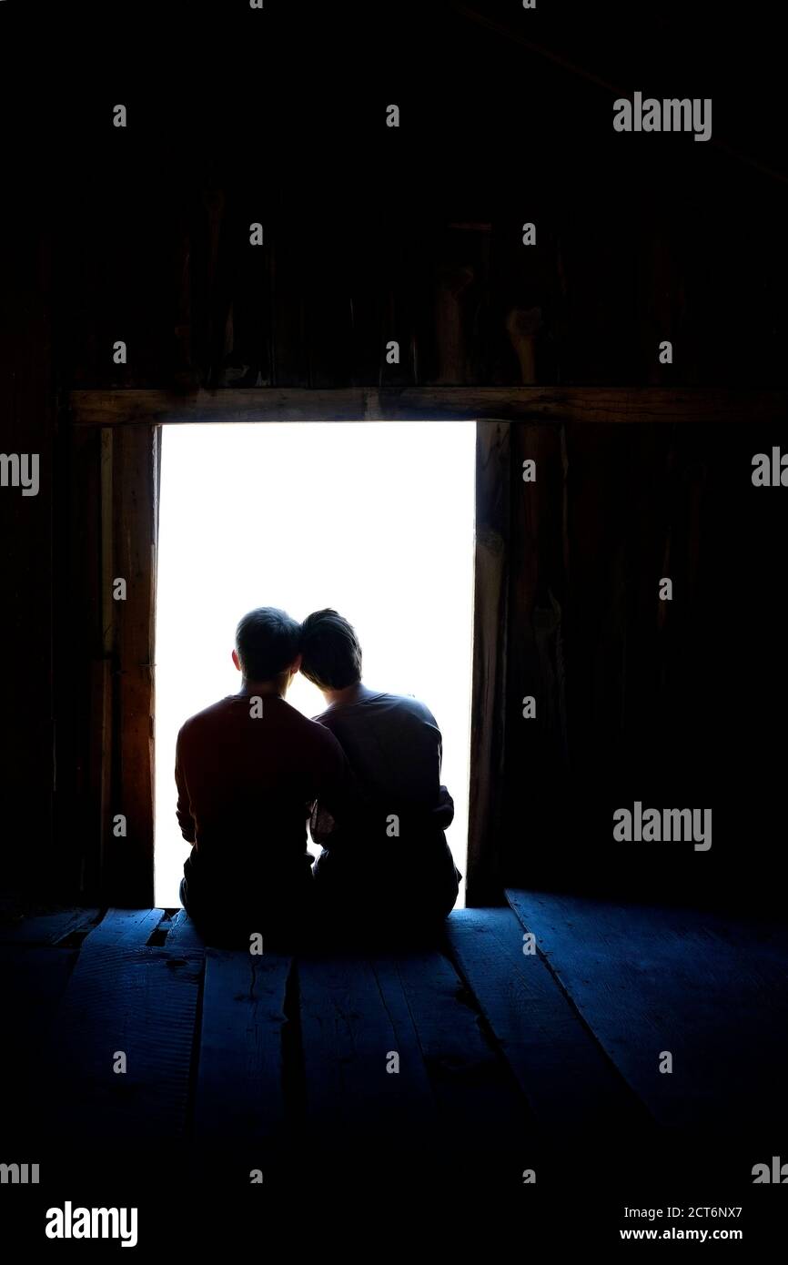 Coppia seduta insieme amore silhouette in vecchio fienile finestra legno Foto Stock