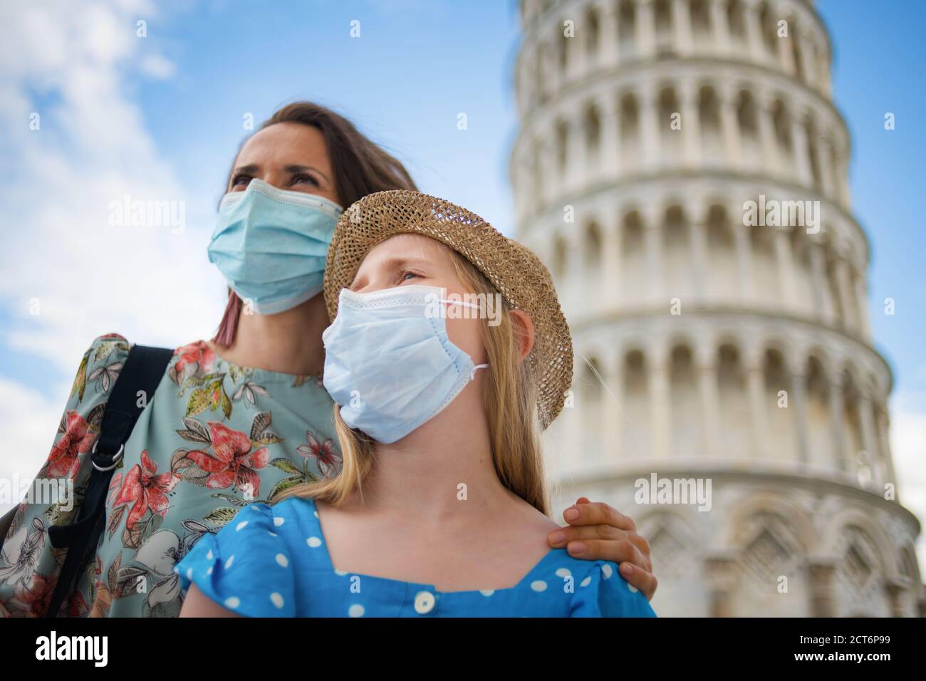 Viaggio durante la pandemia del coronavirus. Giovani turisti di madre e figlia con maschere mediche che guardano in lontananza vicino alla torre pendente a Pisa, Italia. Foto Stock