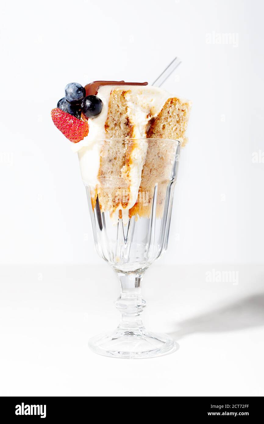 Pezzo di pan di Spagna con panna e bacche su sfondo bianco. Concetto di festa di compleanno Foto Stock
