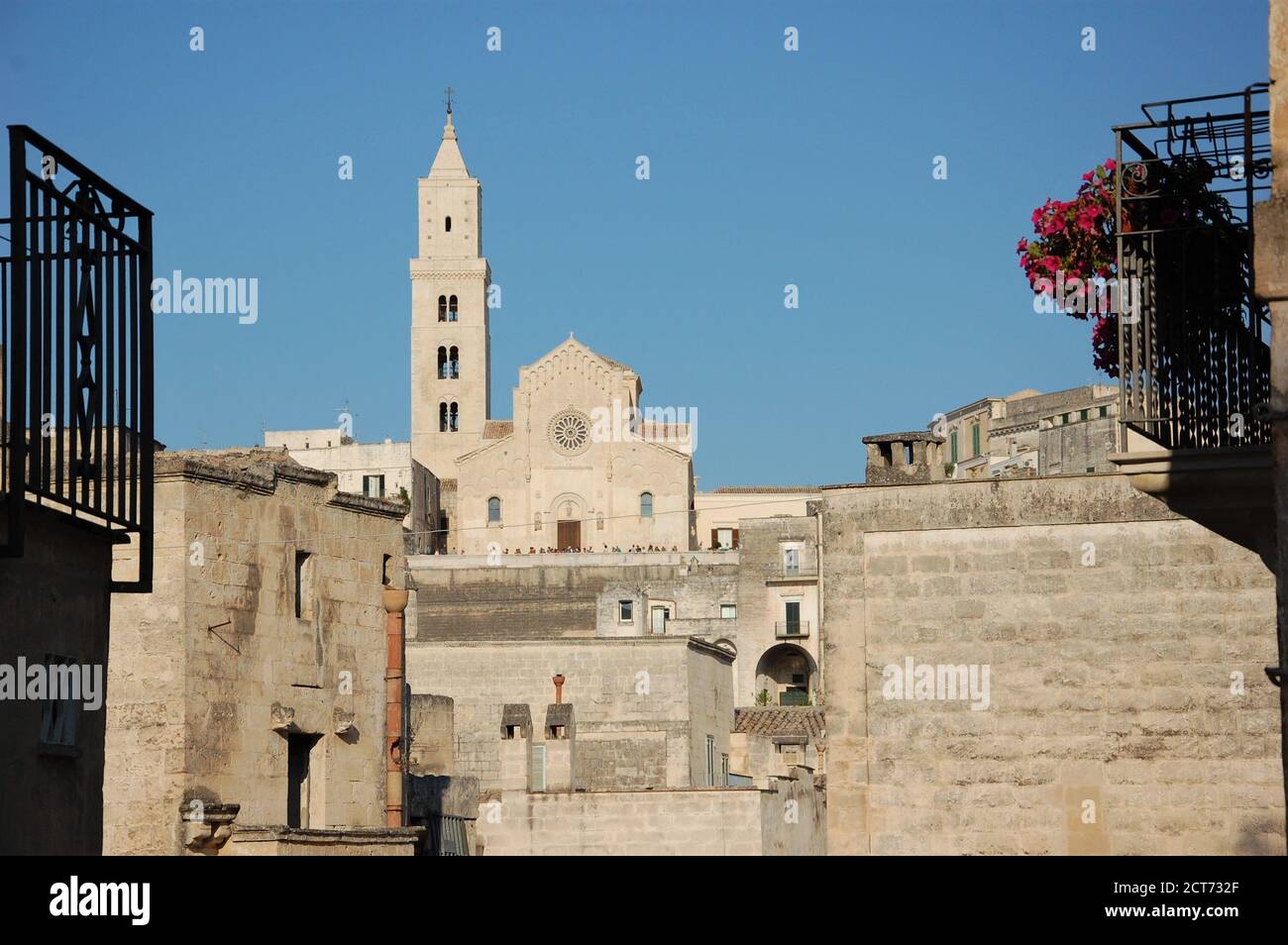 Vista panoramica sulla città del duomo di Matera in collina e case di pietra intorno con cielo blu chiaro sopra e. due ringhiere in ferro nero in primo piano Foto Stock
