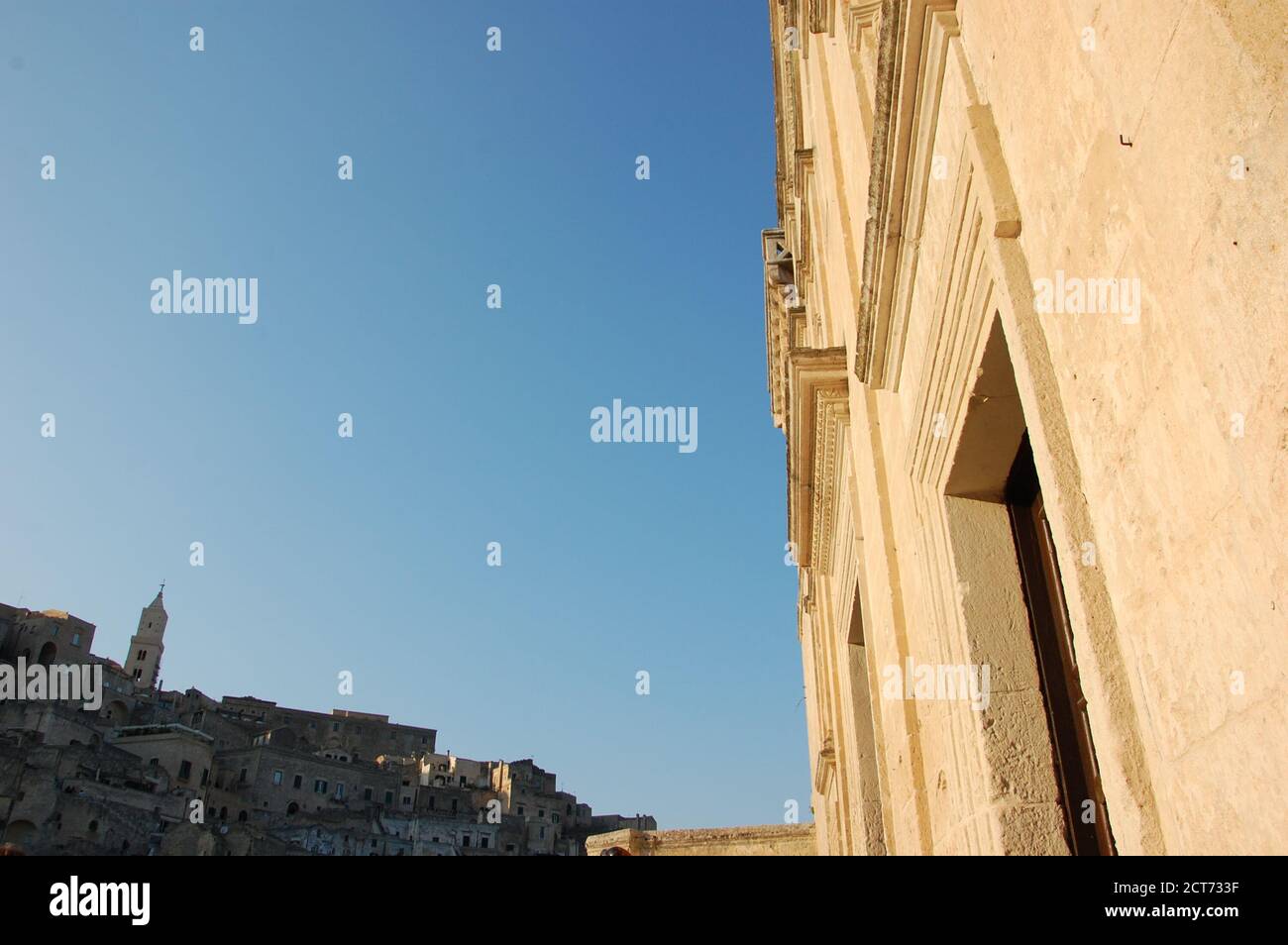 Vista panoramica urbana di Matera con la facciata della chiesa Da un lato e le case e la Cattedrale dall'altro e. cielo blu chiaro al centro Foto Stock