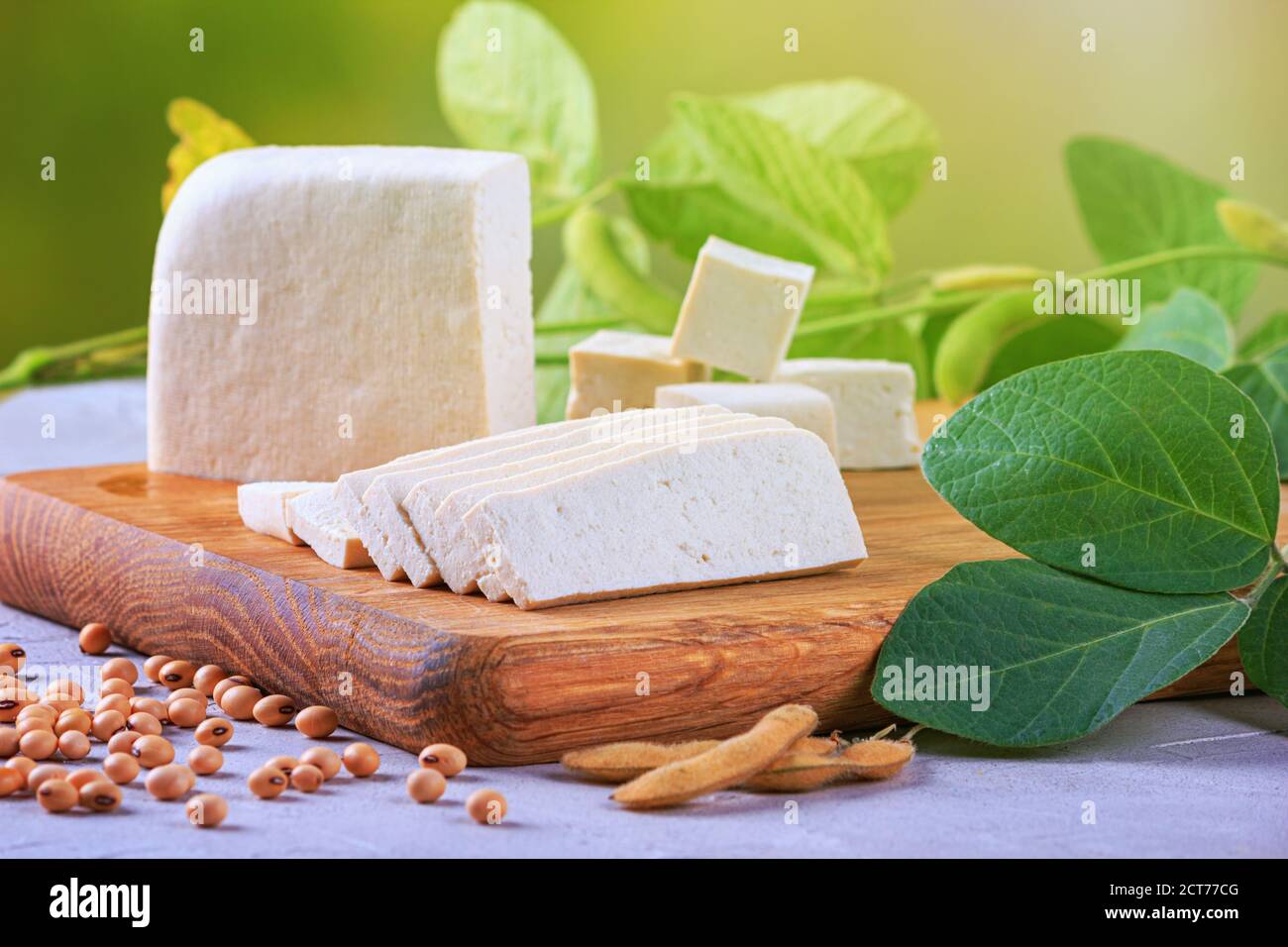 Tofu, noto anche come cagliata di fagioli, tagliato su un tagliere di legno, primo piano con fuoco selettivo Foto Stock