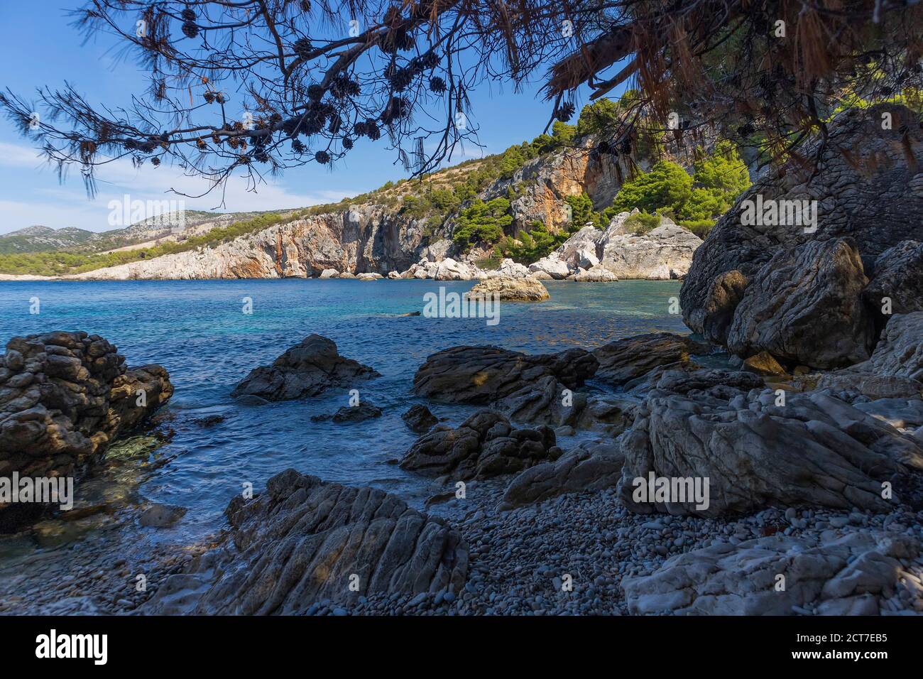Incredibile natura dell'isola di Hvar con ripide scogliere rocciose che si innalzano sull'appartata spiaggia 'Zarace', circondata da turchese, mare adriatico Foto Stock