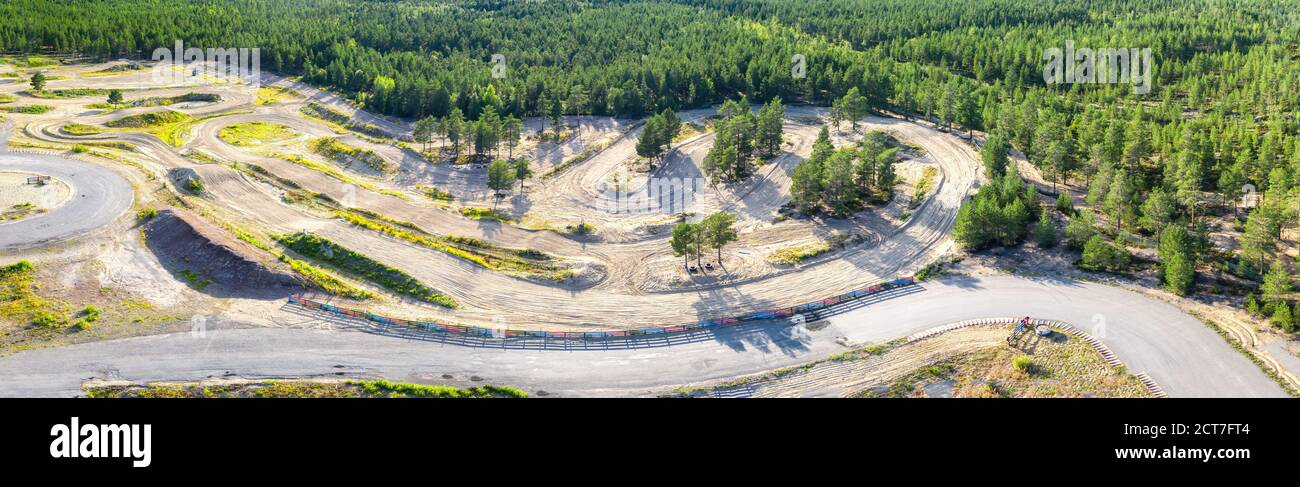 Panorama aereo mozzafiato della foresta di pini verdi scandinavi e parte della pista di allenamento speedway sottostante. Giorno estivo soleggiato. Tipica scansione Northern Foto Stock