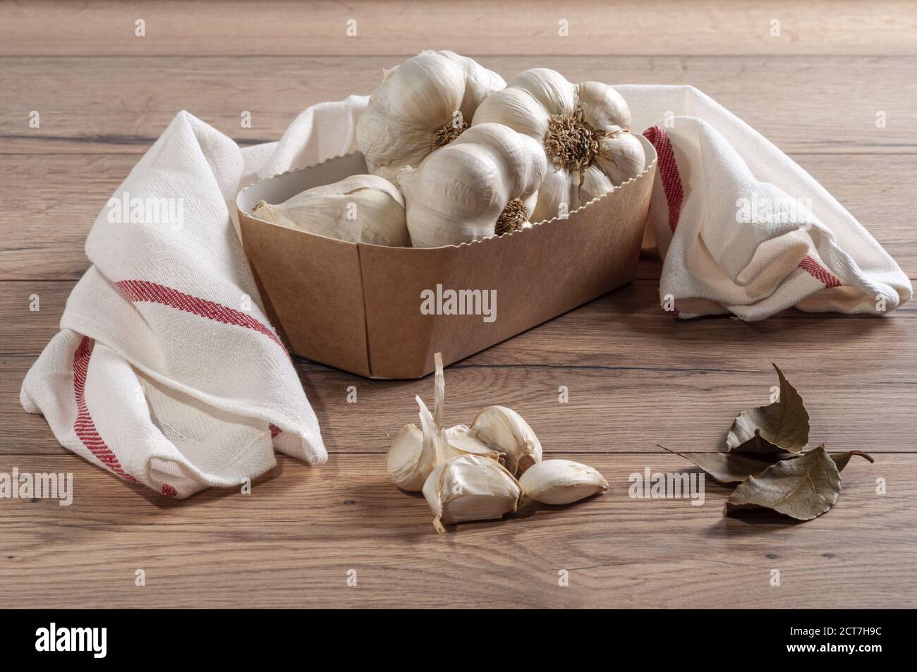 Spicchio di bulbi interi all'aglio in un contenitore di carta sopra il tavolo con un tovagliolo Foto Stock