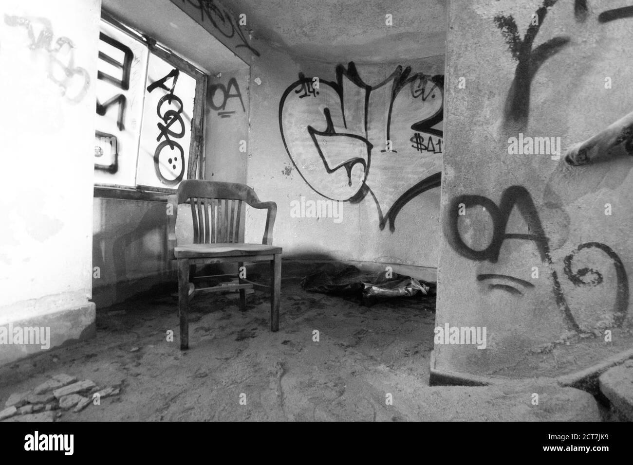 Una vecchia sedia di legno all'interno di un edificio abbandonato pieno di Detriti e polvere Foto Stock
