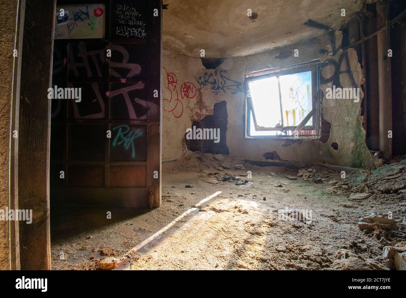 Una vecchia finestra in un edificio abbandonato pieno di polvere E detriti con luce che brilla attraverso Foto Stock