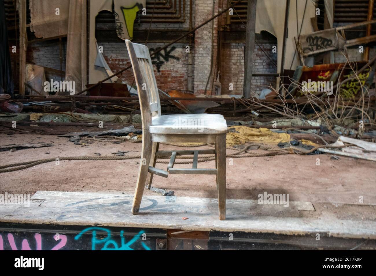Una sedia di legno vecchia e rotta sul palco di Un Teatro abbandonato Foto Stock