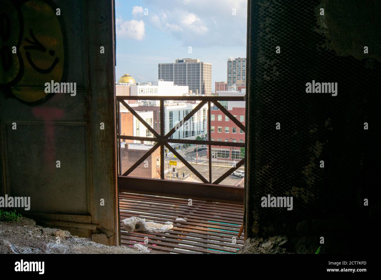 Si affaccia su una porta aperta in un vecchio edificio abbandonato In uno skyline della città Foto Stock