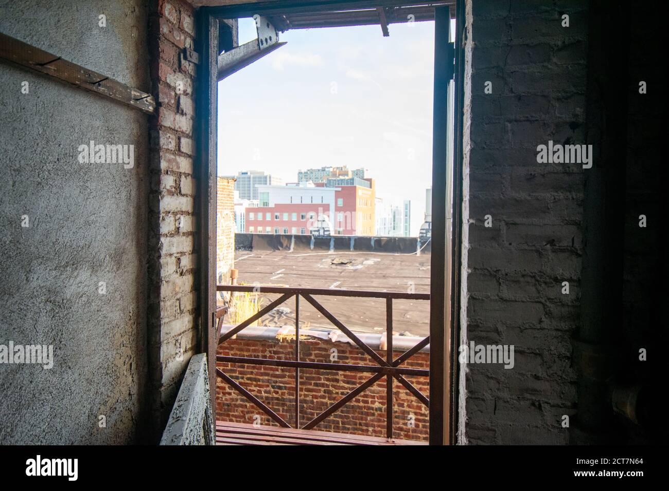 Si affaccia su una porta aperta di un edificio abbandonato Una fuga dal fuoco presso uno skyline della città Foto Stock