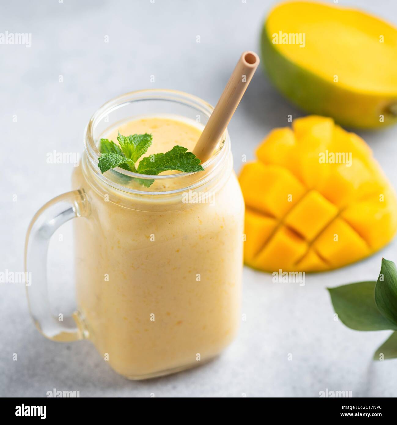 Frullato di mango, lassi di mango in un vaso di vetro con cannuccia di bambù Foto Stock