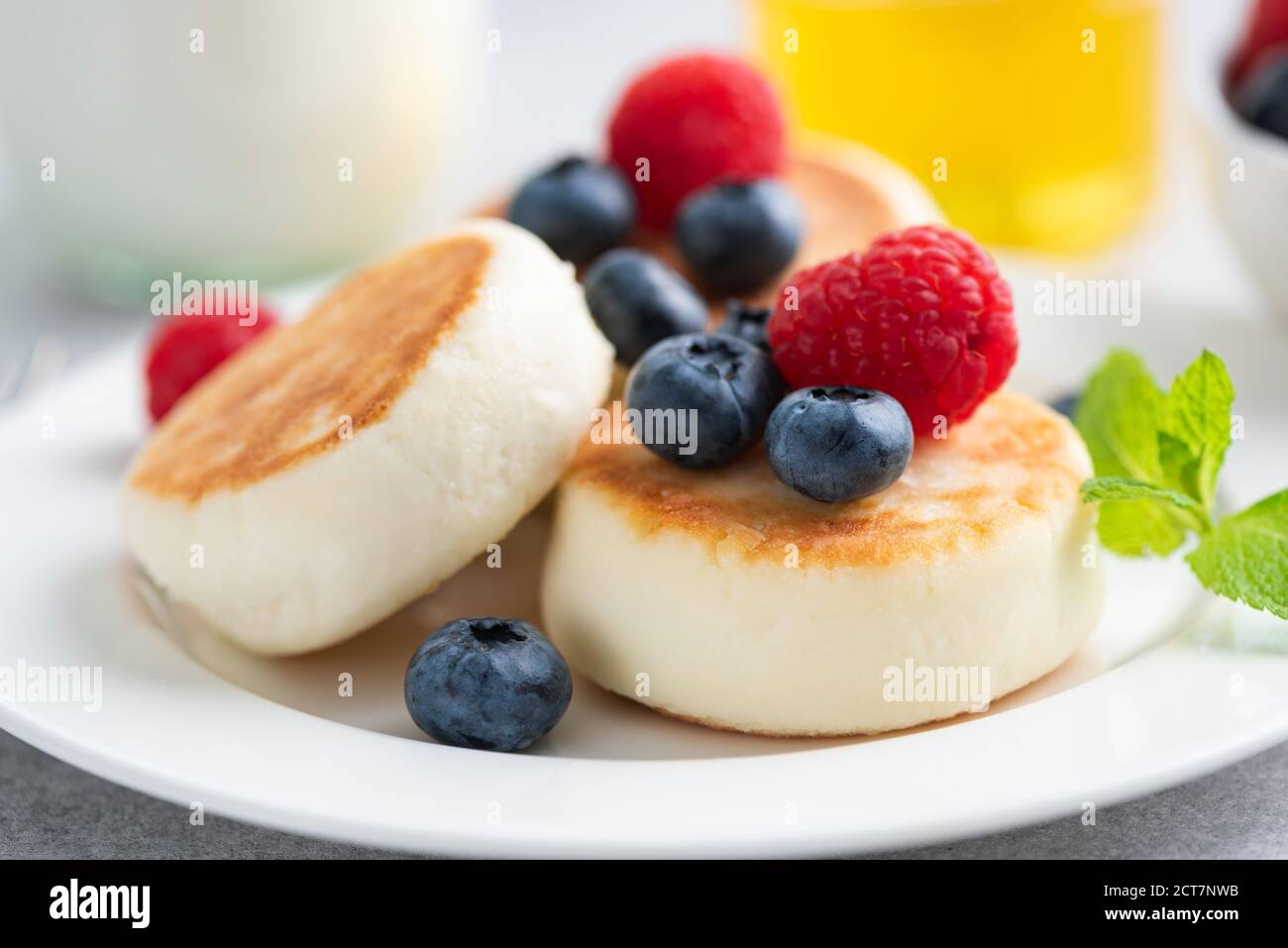 Syrniki, frittelle di formaggio cottage con frutti di bosco su un piatto, vista closeup. Colazione o dessert Foto Stock