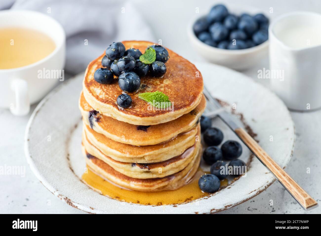 Pancake con mirtilli e miele su un piatto. Colazione frittelle impilate con frutti di bosco Foto Stock