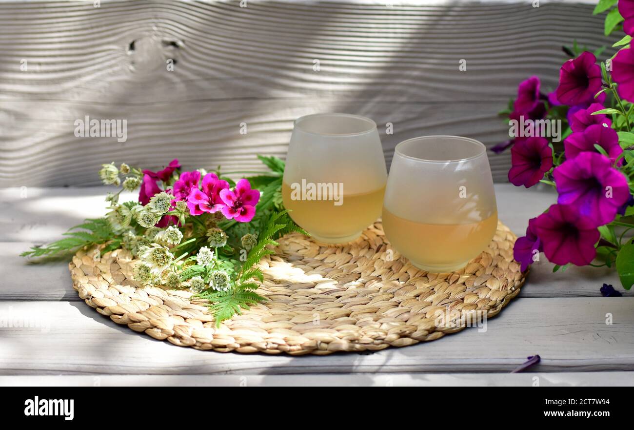 Rinfrescanti bicchieri di vino bianco freddo da gustare in splendida giardino paesaggistico cortile impostazione in bella calda giornata estiva a. casa Foto Stock