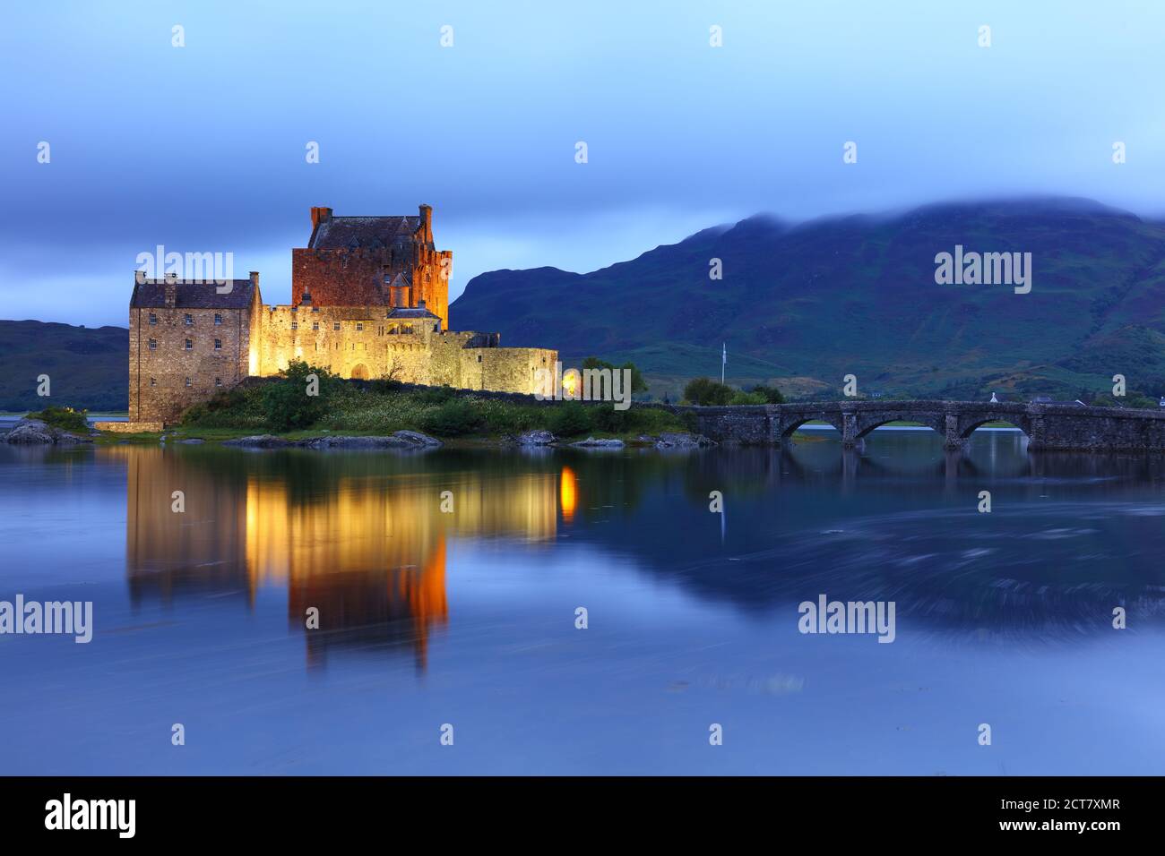 Eileen Donan Castle illuminato dopo il tramonto in una serata nuvolosa, West Highlands, Scozia, Regno Unito Foto Stock