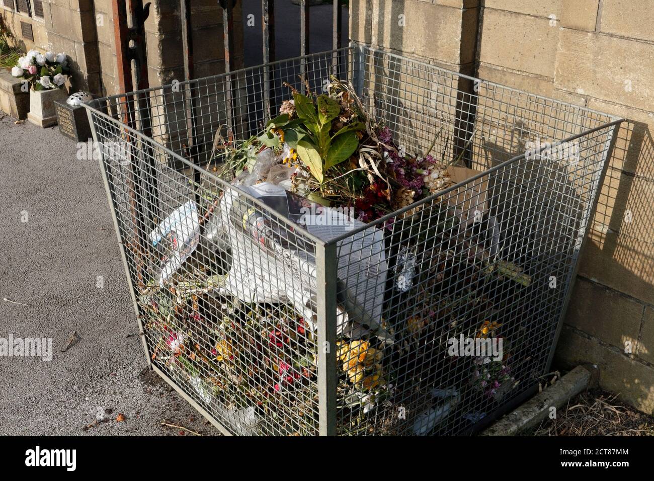 Bidone in cimitero pieno di fiori scartati Foto Stock