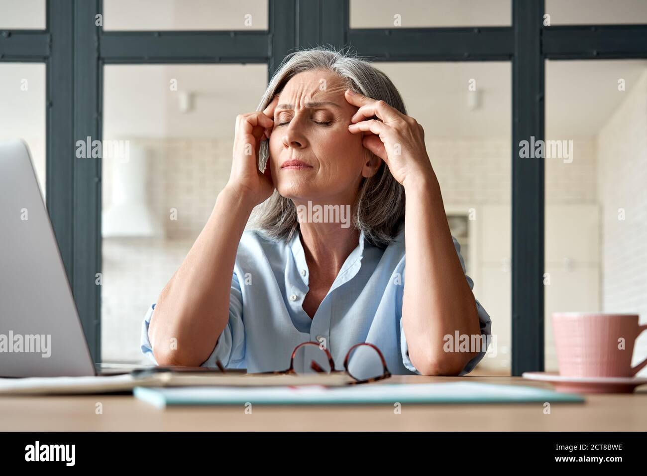 Stanco ha stressato la vecchia donna matura di affari che soffre di mal di testa al lavoro. Foto Stock