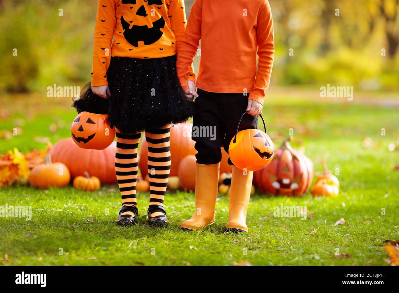 I bambini trick o treat su Halloween. I bambini in costume di strega nero e arancione e cappello giocano con zucca e ragno nel parco autunnale. Vestito ragazzo e g Foto Stock