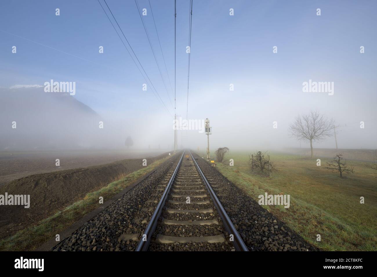 I binari della ferrovia nella nebbia e montagna in Ticino, Svizzera. Foto Stock