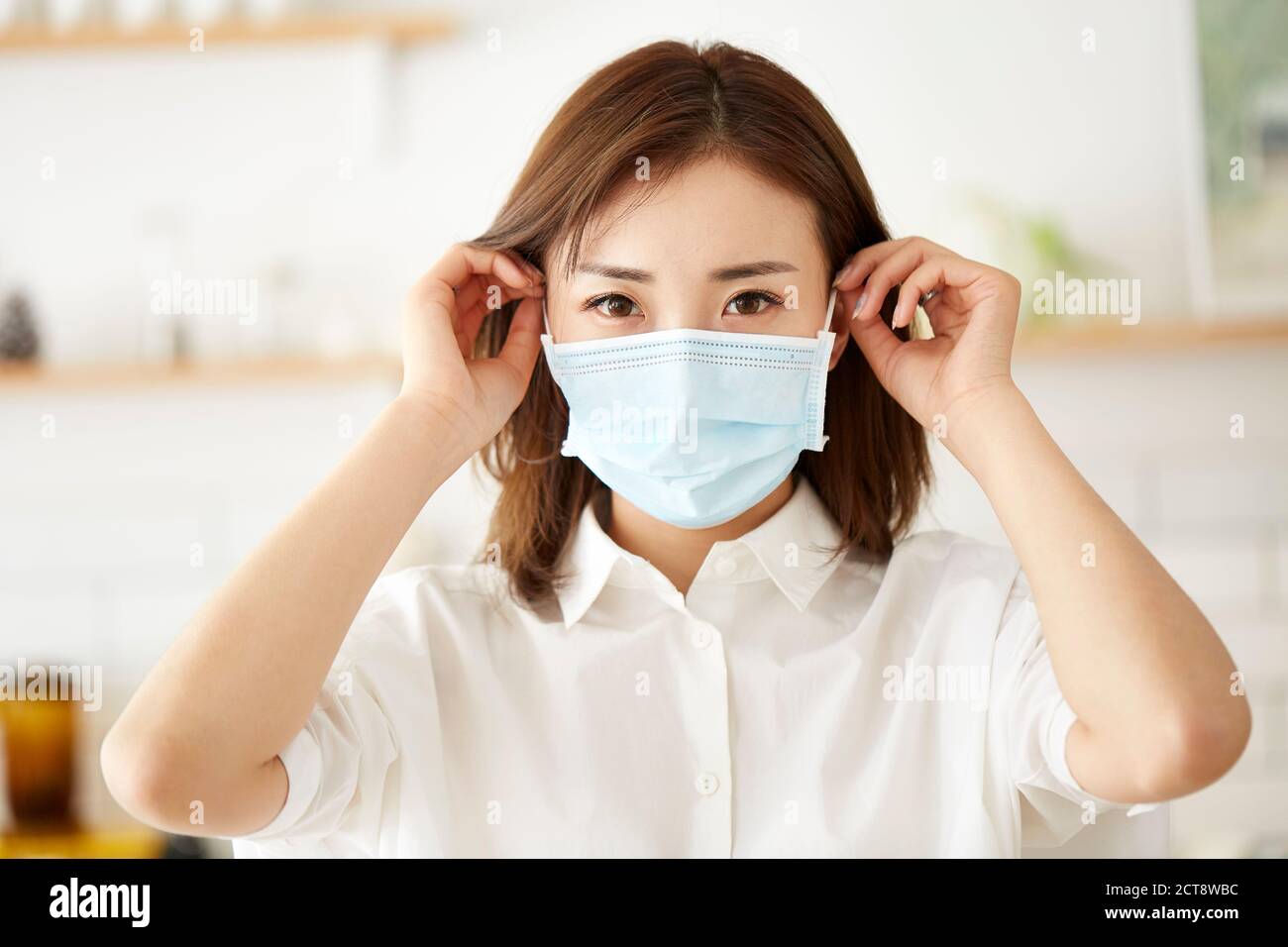 bella giovane donna asiatica che mette su una maschera sul viso Foto Stock