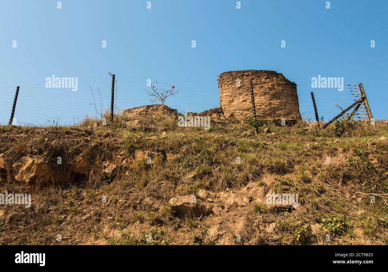 Rovina di pietra sminuzzante su ripida collina dietro recinzione elettrica Foto Stock