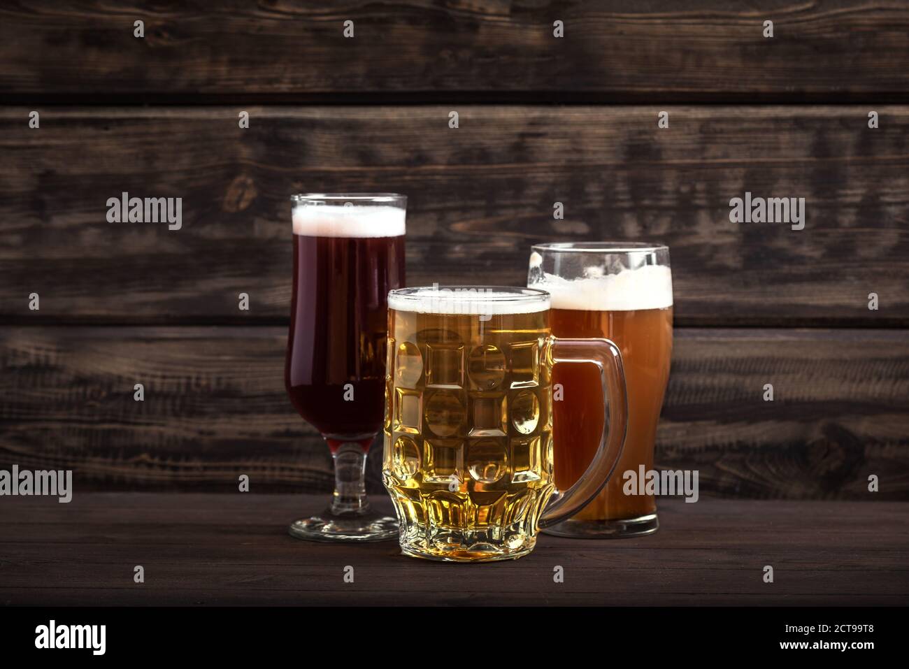 Vari tipi di birra alla spina in bicchieri e tazza su tavolo di legno, spazio di copia. Birra fresca. Foto Stock