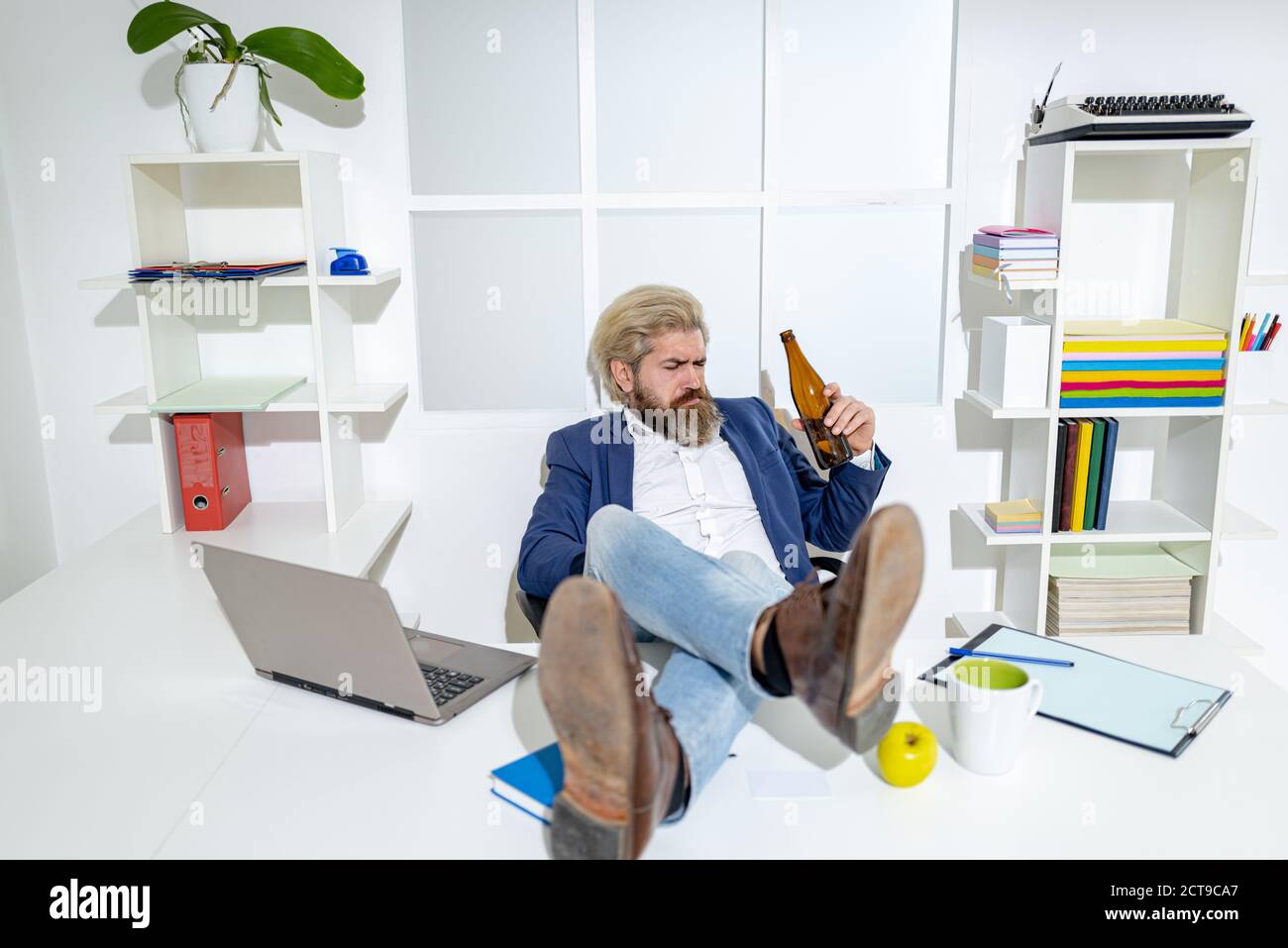 Fine della giornata lavorativa. Uomo d'affari ubriaco che tiene una bottiglia di alcool. Foto Stock