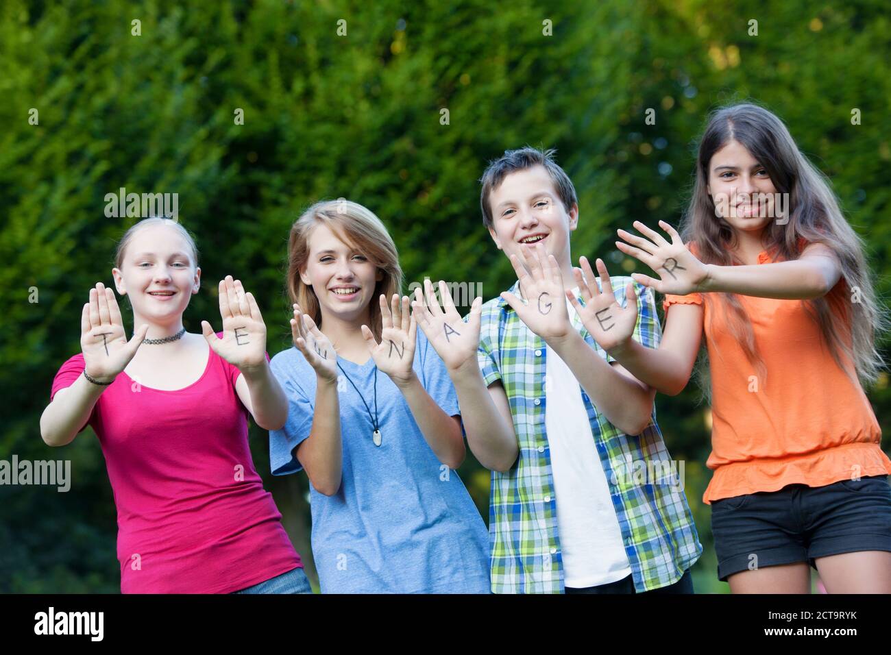 Tre ragazze e un ragazzo che mostra insieme la parola adolescente sui loro palmi Foto Stock