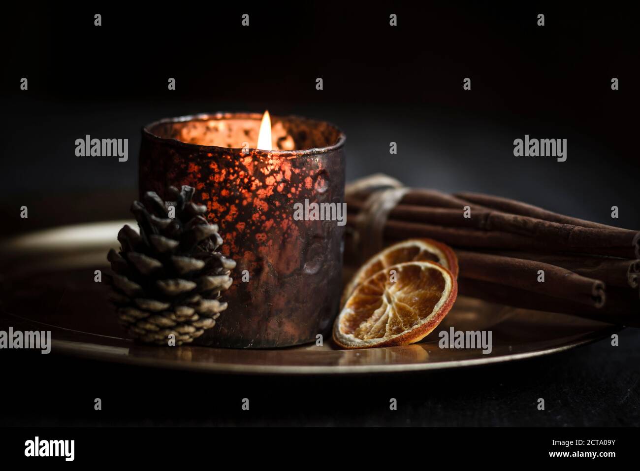 Decorazione di natale con the light candle, bastoncini di cannella, fette di arance essiccate e cono su piastra, studio shot Foto Stock