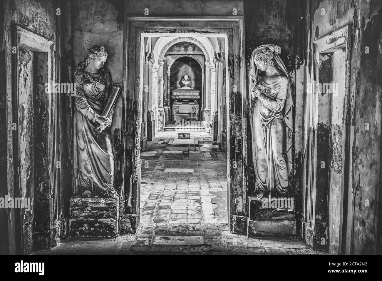 cimitero lungo corridoio in bianco e nero con due statue Foto Stock