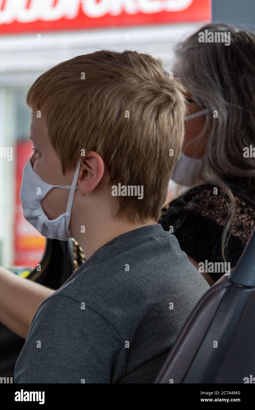 Un ragazzo che indossa una maschera facciale su un autobus Durante la pandemia di Coronavirus Foto Stock
