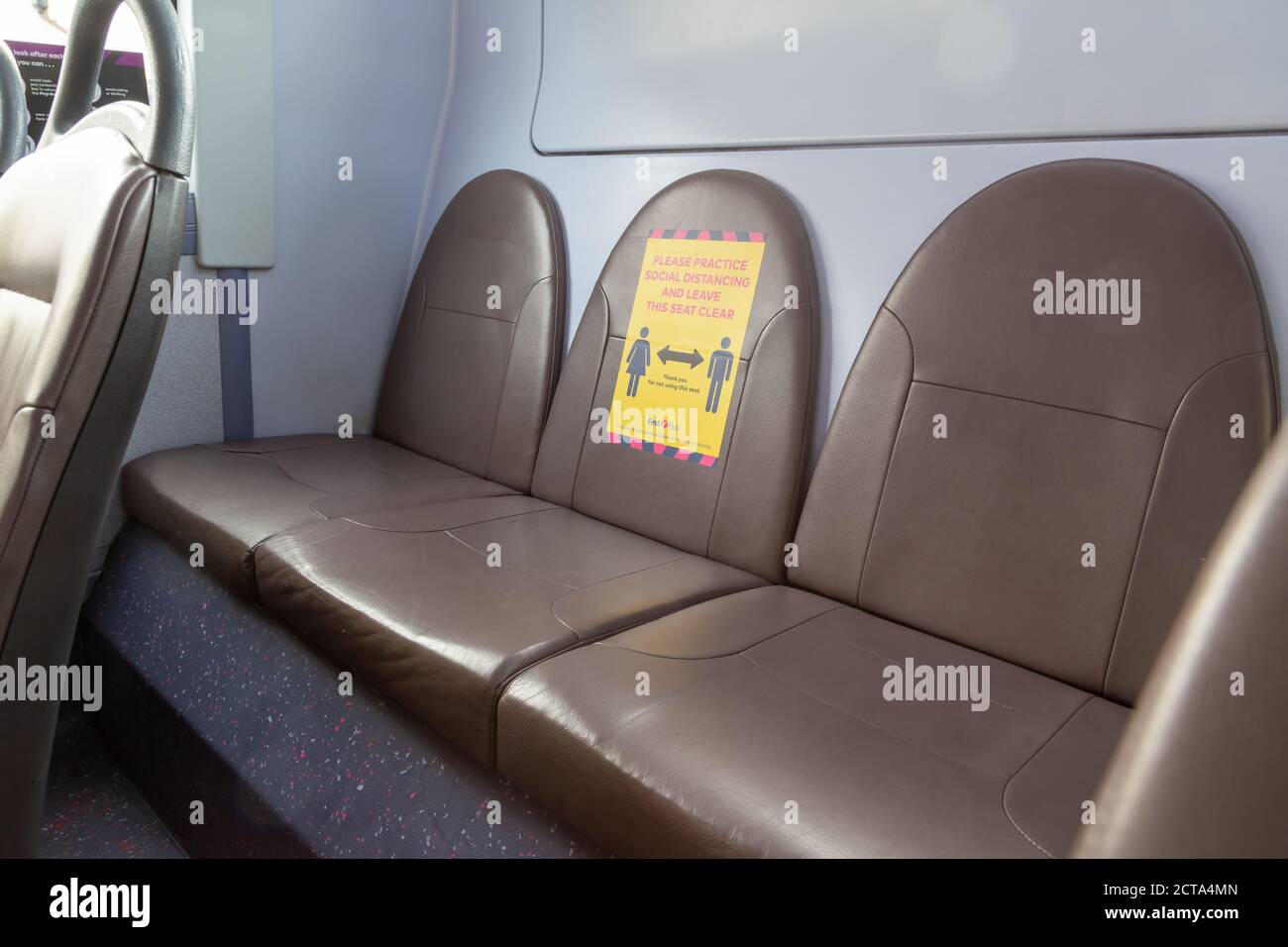 I sedili posteriori di un autobus con un segno incoraggiante distanza sociale durante l'epidemia di coronavirus Foto Stock