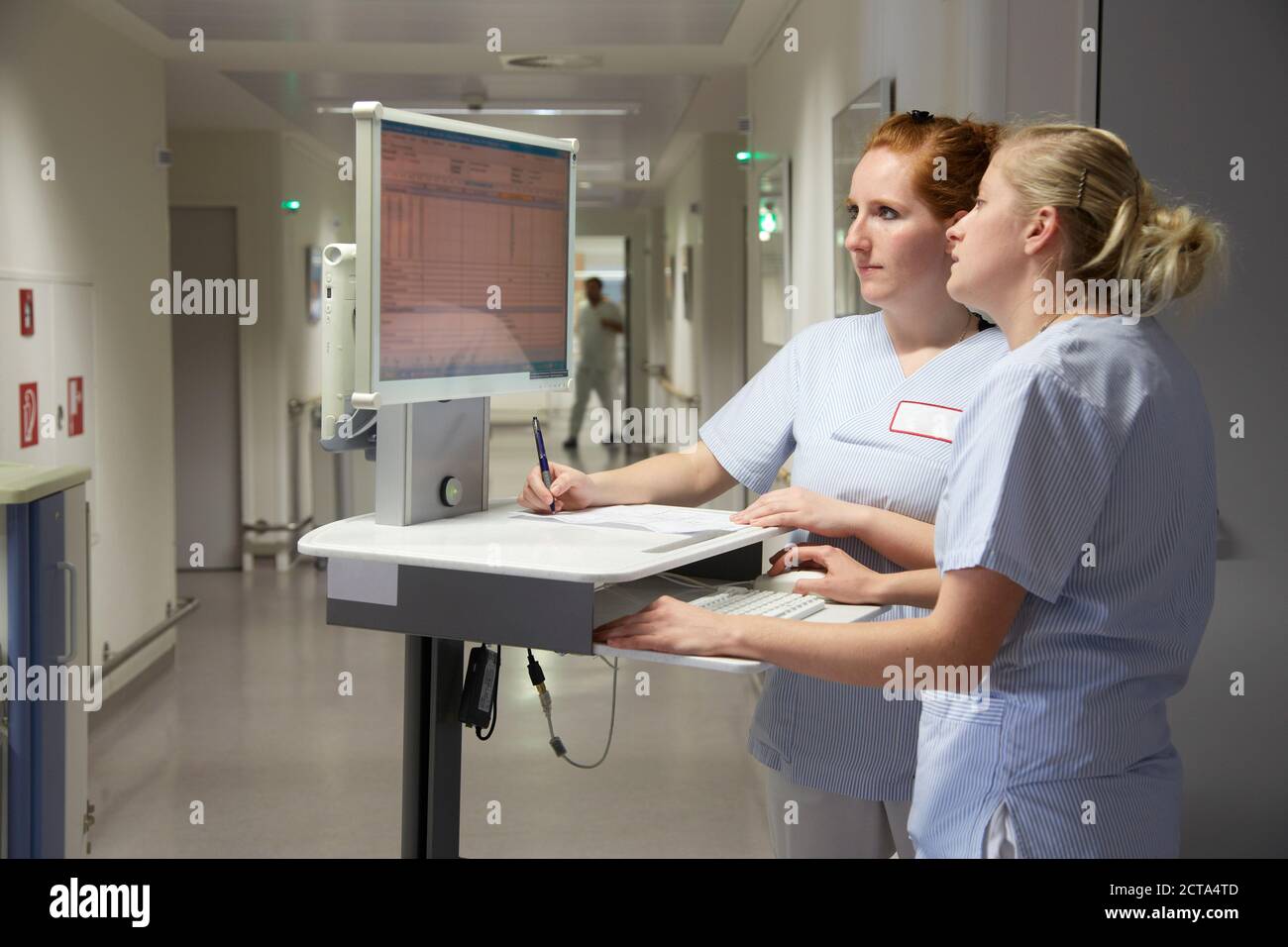 Germania, Freiburg, infermieri con computer mobile deskte, controllo dei dati del paziente Foto Stock