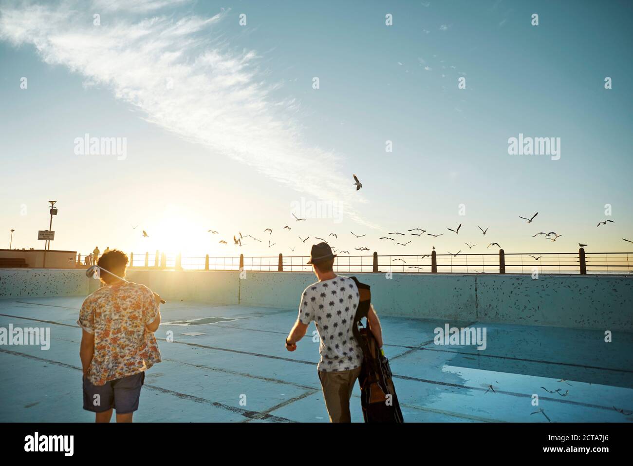 Due amici a piedi con borsa da golf in vuote piscina Foto Stock