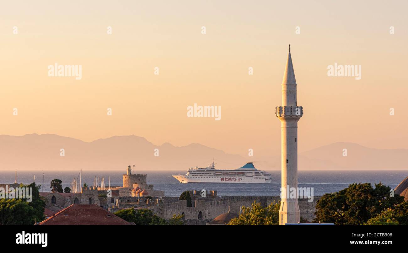 Una nave da crociera naviga attraverso le mura della città vecchia di Rodi e il minareto della Moschea Ibrahim Pasha a Rodi, Grecia Foto Stock