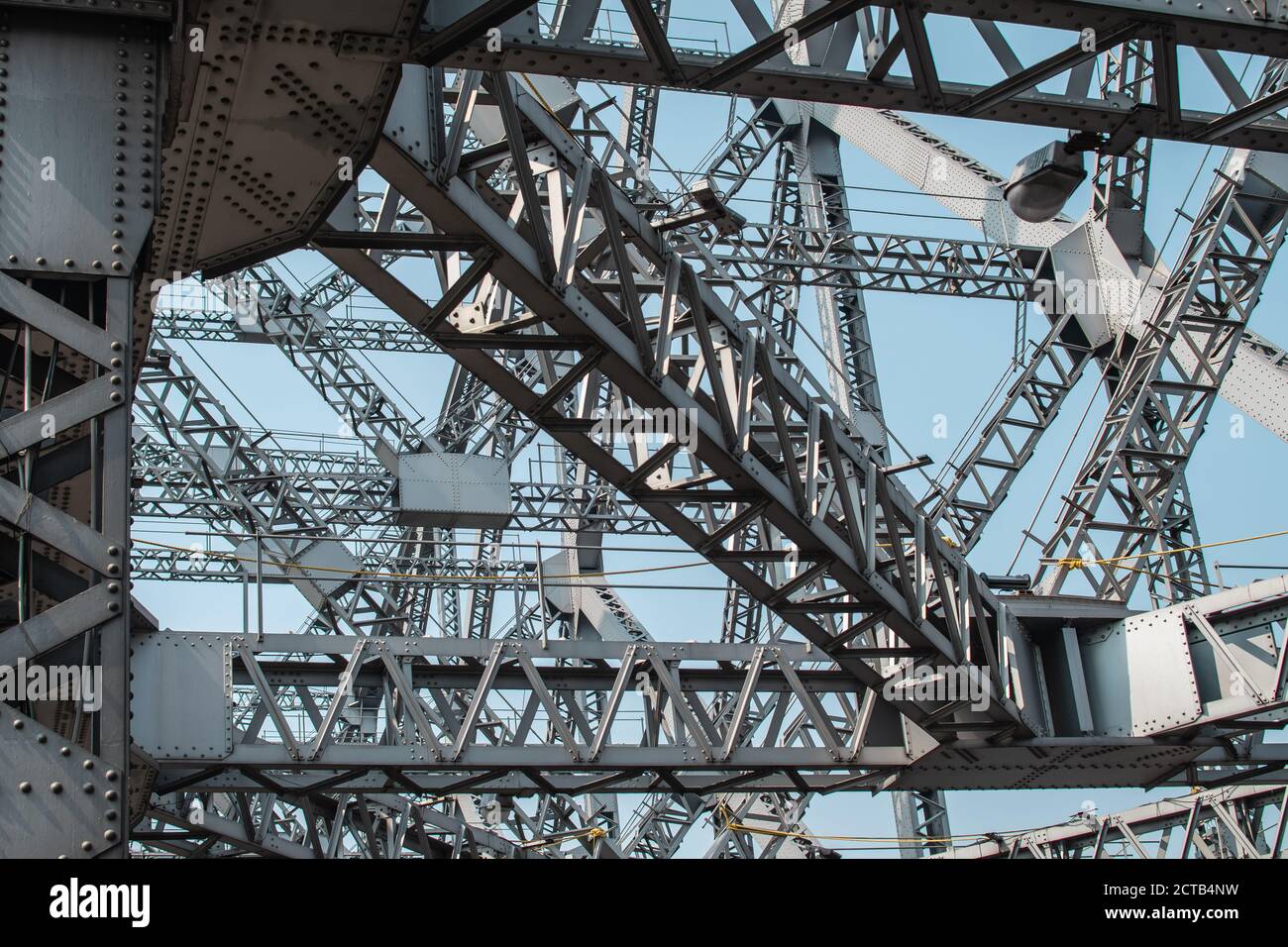 Guardando verso l'alto le travi metalliche e le forme triangolari del ponte Howrah a Kolkata, India Foto Stock
